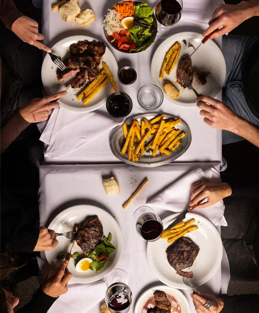 Mesa servida con bife, papas fritas y vino