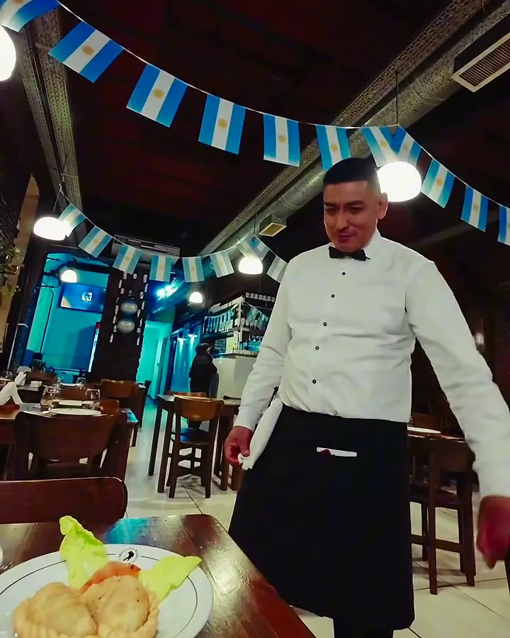 Mozo de moño en el salón con banderines argentinos